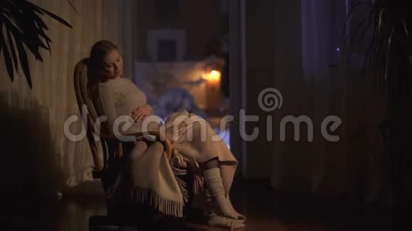 微笑的孕妇长发坐在黑暗的房间里的摇椅上抚摸她的腹部视频的预览图