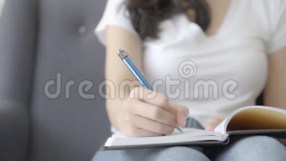 特写亚洲女人放松躺在沙发上写书写日记在家里的沙发上视频的预览图