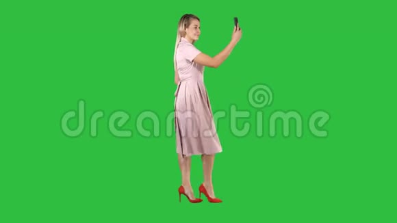 可爱甜美华丽漂亮令人惊叹可爱漂亮穿着漂亮的女士在绿色屏幕上散步时自拍视频的预览图