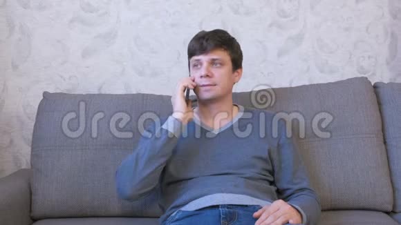 男人在手机上拨一个号码坐在沙发上等待答案视频的预览图