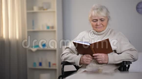 坐在轮椅上看书的老妇人在寻找眼镜视力不好视频的预览图
