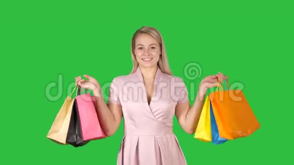 购物的女人开心地微笑着拿着购物袋我一边走在绿色的屏幕上色度键视频的预览图