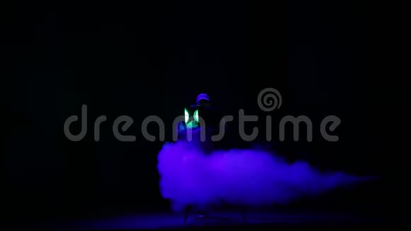 一个女照明师用一阵烟把一束光从聚光灯射进大厅视频的预览图
