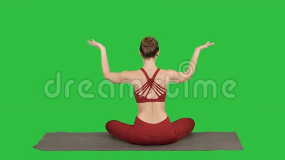 年轻运动的女人坐在莲花的姿势双手在她的头上方的绿色屏幕Chroma键视频的预览图