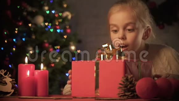 兴奋的女孩看着桌子上的圣诞礼物装饰得很好视频的预览图