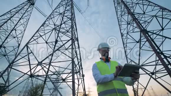 一个高大的电塔和一个男技术员在旁边工作视频的预览图