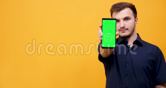 年轻人手里拿着绿色屏幕的手机视频的预览图