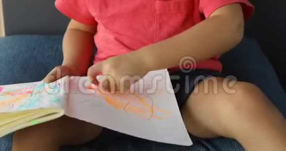 躺在地上用铅笔在纸上画可爱的孩子的侧视视频的预览图