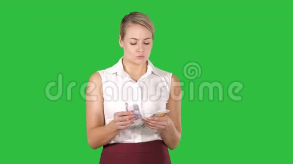 漂亮的年轻女人数钱花在绿色屏幕上Chroma键视频的预览图