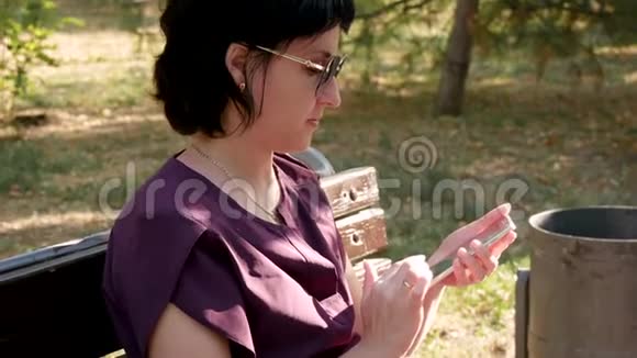 夏天公园里一个戴着太阳镜的黑发女孩坐在长凳上看着手机屏幕摸了摸手机视频的预览图