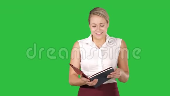女人拿着打开书或笔记本大声地在绿色屏幕上读一些东西铬键视频的预览图