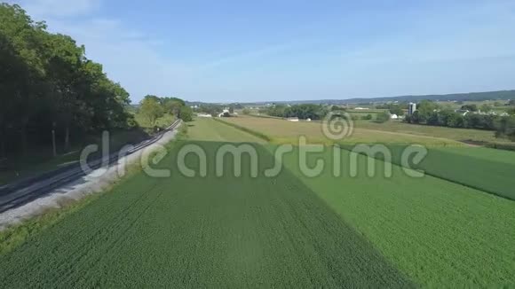 空中景观靠近阿米什乡铁路轨道旁的绿色农业农场土地视频的预览图