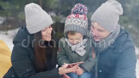 一家人带着儿子在冬林的电话里看照片圣诞快乐视频的预览图