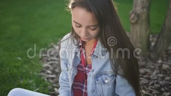 年轻的女大学生坐在校园里做作业视频的预览图
