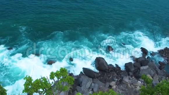 海浪以浪花和白色泡沫破碎到岩石悬崖海浪飞溅到岩石岛的顶部绿松石视频的预览图
