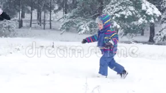 一个快乐的孩子跑到他的母亲身边母亲把他高高举起在下雪的冬天亲吻他视频的预览图