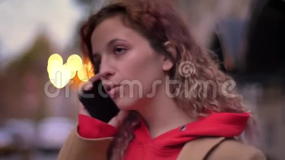 侧面特写照片年轻的金发白种人女孩专注地在模糊的夜晚城市用手机交谈视频的预览图
