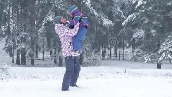 一位快乐的母亲把儿子抱在怀里在一个美丽的冬天雪天在公园里亲吻他视频的预览图