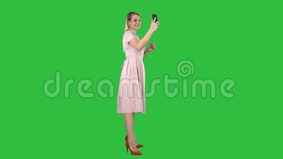 漂亮的女人在绿色屏幕上看着她的手机Chroma键视频的预览图