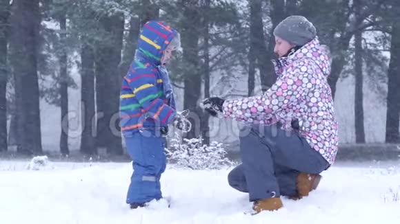 妈妈在一片冬林的手里给孩子递了一个雪球视频的预览图