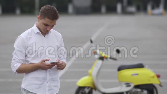 带电话的年轻人站在一辆摩托车旁边视频的预览图