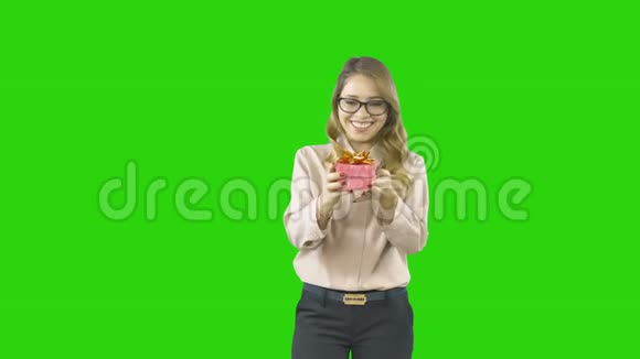 一位穿着节日服装的年轻女子手里拿着一个小盒子手里拿着一件礼物打开它充满节日的气氛视频的预览图