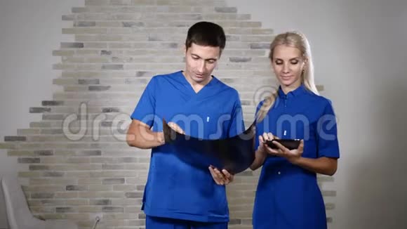 一队穿着蓝色制服的年轻医生在医疗诊所看x光图像4k视频的预览图