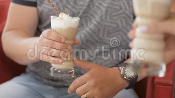 一个男人和一个女孩坐在咖啡馆里拿着大玻璃杯和咖啡鸡尾酒视频的预览图