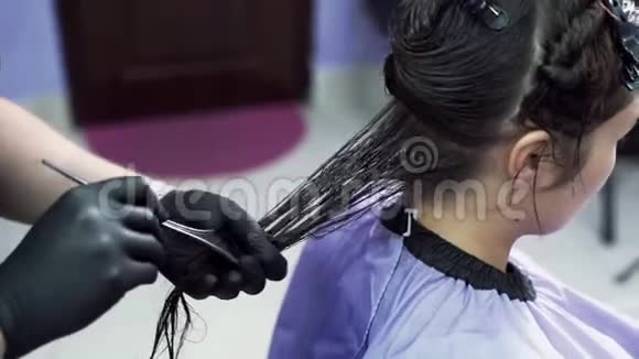 这位发型师的一个特写慢镜头与客户合作他的头发戴在手套里用角蛋白刷涂在女孩身上视频的预览图