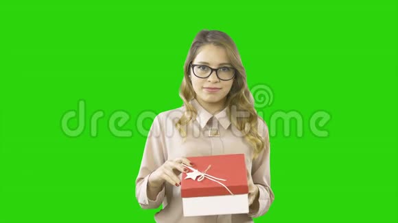 年轻的姑娘手里拿着一个盒子手里拿着一个礼物她打开了盒子对一个孤立的绿色表示深深的敬意视频的预览图