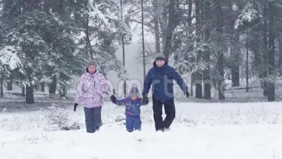 在下雪的冬天幸福的一家人跑到镜头前妈妈爸爸和孩子在外面玩视频的预览图