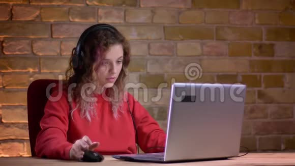 穿着红色连帽衫的年轻女性博客写手的肖像在bricken墙背景下带着令人不快的悲伤手表变成了笔记本电脑视频的预览图