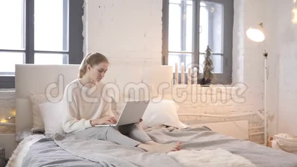颈部疼痛的疲惫少女在床上做手提电脑视频的预览图