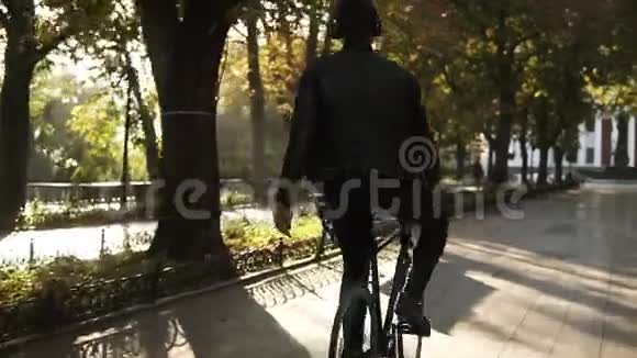带着耳机的年轻人骑着自行车在公园里徒步旅行的黑色自行车一边听着一边用手骑马视频的预览图