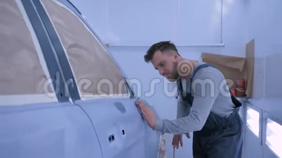 汽车油漆工在加油站修理工作期间在油漆室手工喷漆后打磨汽车视频的预览图