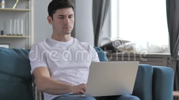 有脊背疼痛的年轻人在笔记本电脑上工作视频的预览图