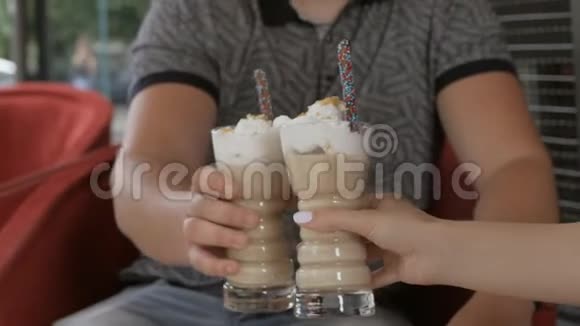 一个男人和一个女孩坐在咖啡馆里拿着大玻璃杯和咖啡鸡尾酒视频的预览图