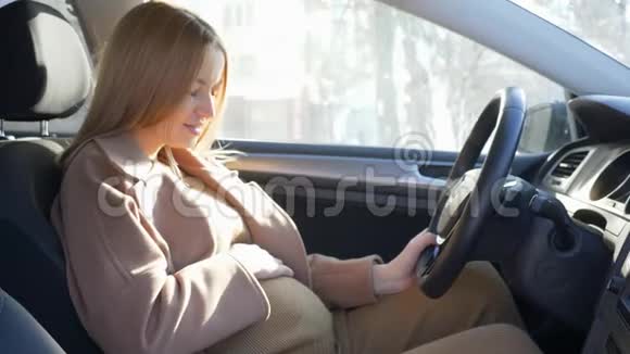孕妇司机穿着安全带坐在车轮后面抚摸着肚子视频的预览图