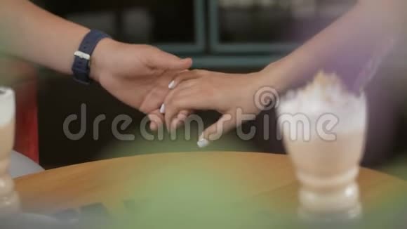 年轻的男人和女人手牵手坐在咖啡馆里它是看不见的视频的预览图