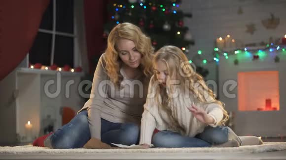 圣诞前夜兴奋的女孩把圣诞老人的信放进信封里拥抱妈妈视频的预览图