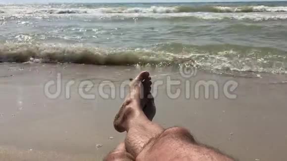 沙滩上的一个男人沐浴在海浪中享受着大海的声音和沙滩上翻滚的波浪视频的预览图