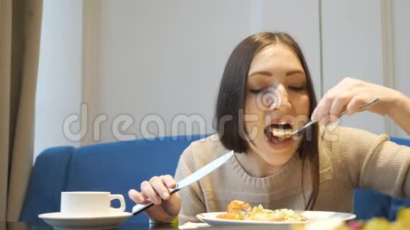 女人用叉子和刀子在咖啡馆里吃蔬菜沙拉视频的预览图