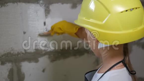 7岁的女孩戴着建筑头盔在建筑工地粉刷墙壁视频的预览图