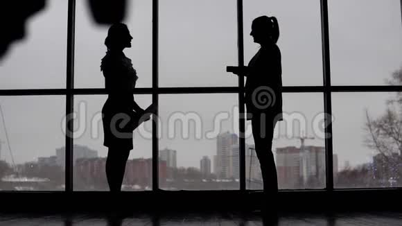 商人来到两个商务妇女站在窗户附近讨论这个项目视频的预览图