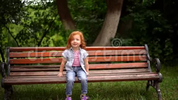微笑的读头孩子坐在公园的长凳上视频的预览图