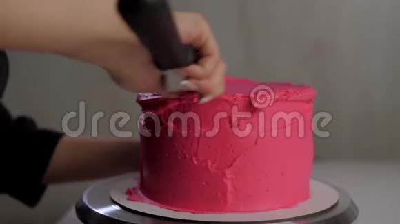 糖果师在蛋糕上放粉红色奶油和糕点匙视频的预览图