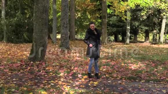 秋天公园穿黑色斗篷的漂亮女孩视频的预览图