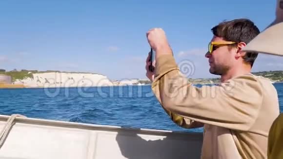 一位穿着米色毛衣的游客在海上的快艇上游泳并在电话上拍照年轻人旅游旅游视频的预览图
