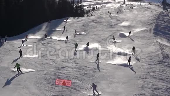 阳光明媚的冬季斜坡有许多滑雪者慢动作视频的预览图