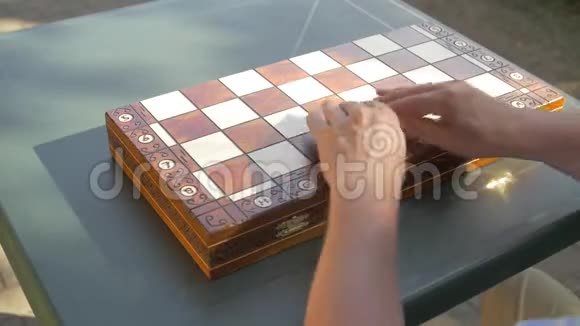 老人打开花园里的棋局盒子把白色的数字并排放在桌子上视频的预览图